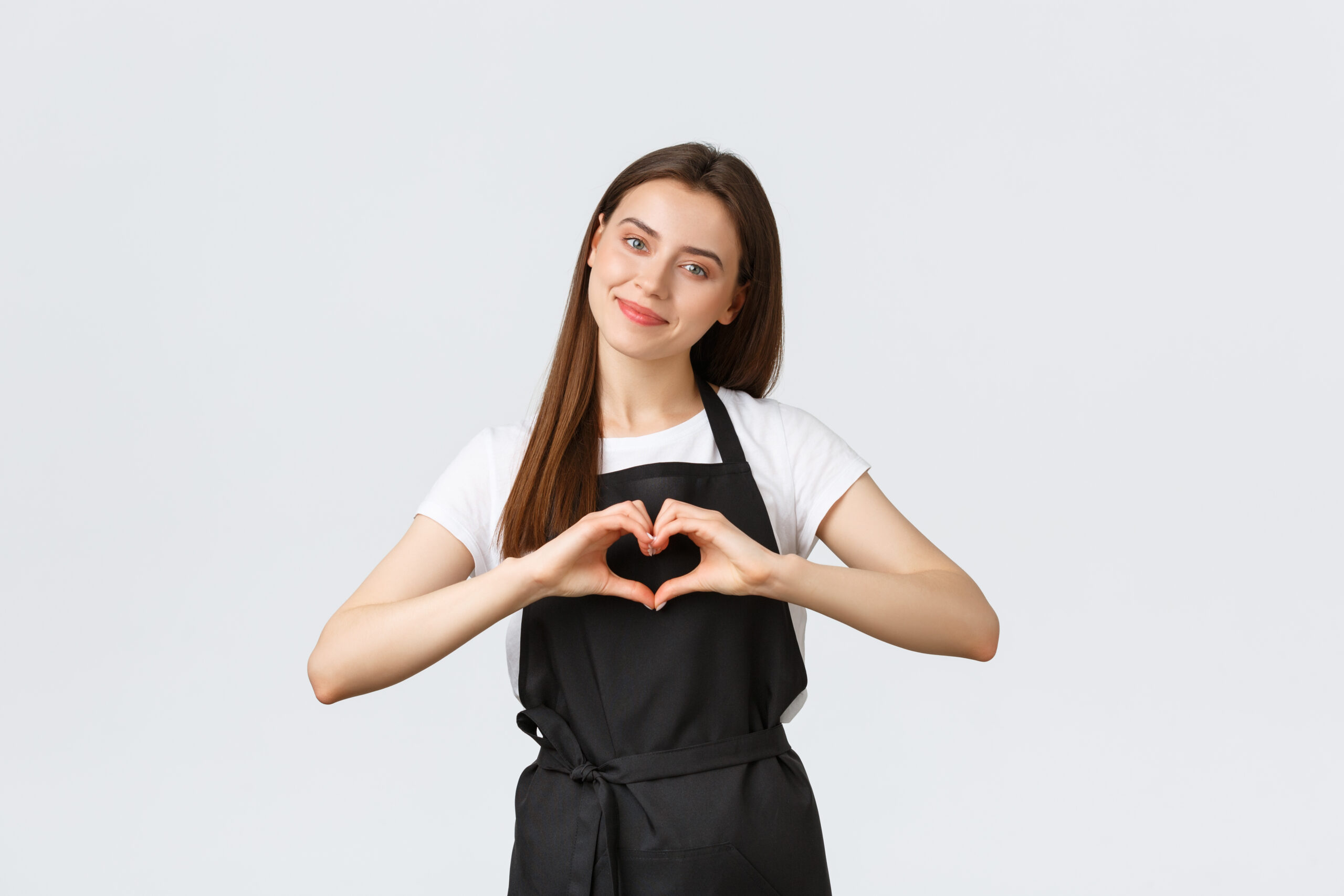 Grocery store employees, small business and coffee shops concept. Lovely friendly-looking barista inviting have taste of new drinks in cafe, showing heart sign to express love for visitors.