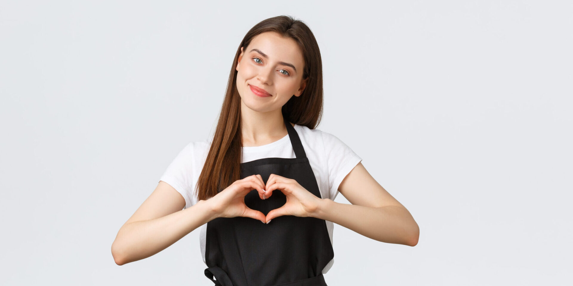 Grocery store employees, small business and coffee shops concept. Lovely friendly-looking barista inviting have taste of new drinks in cafe, showing heart sign to express love for visitors.