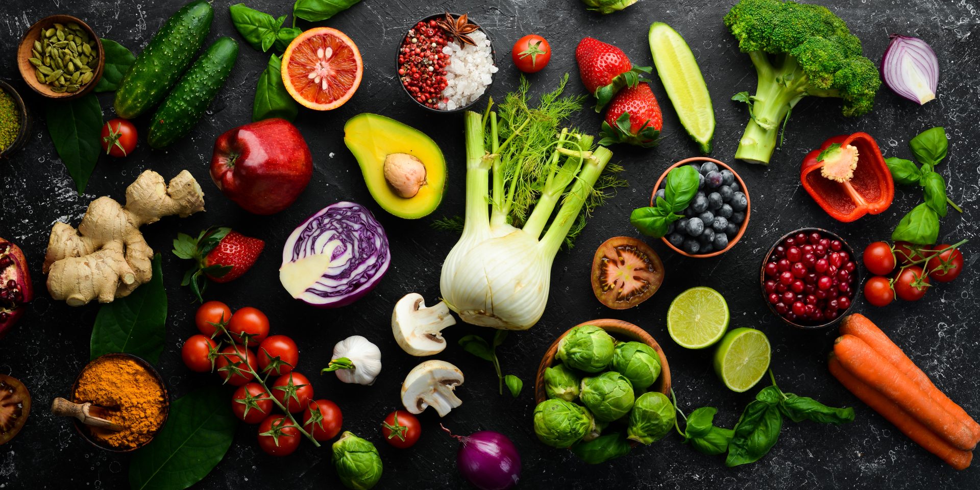 Healthy eating concept: vegetables and fruits on black stone background. Top view. Free space for your text.